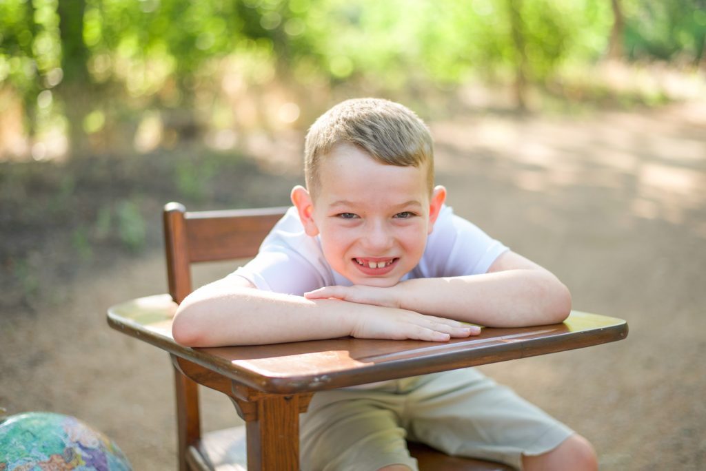 boy leans on desk during mini sessions in Texas