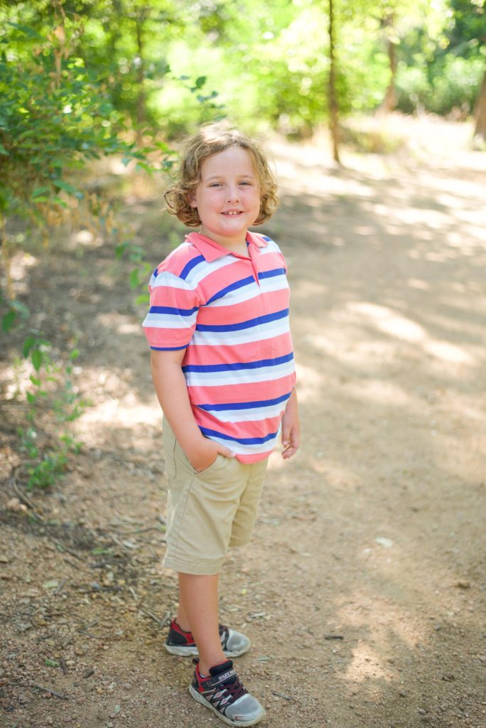 young boy in striped polo poses on trail in Beard Park