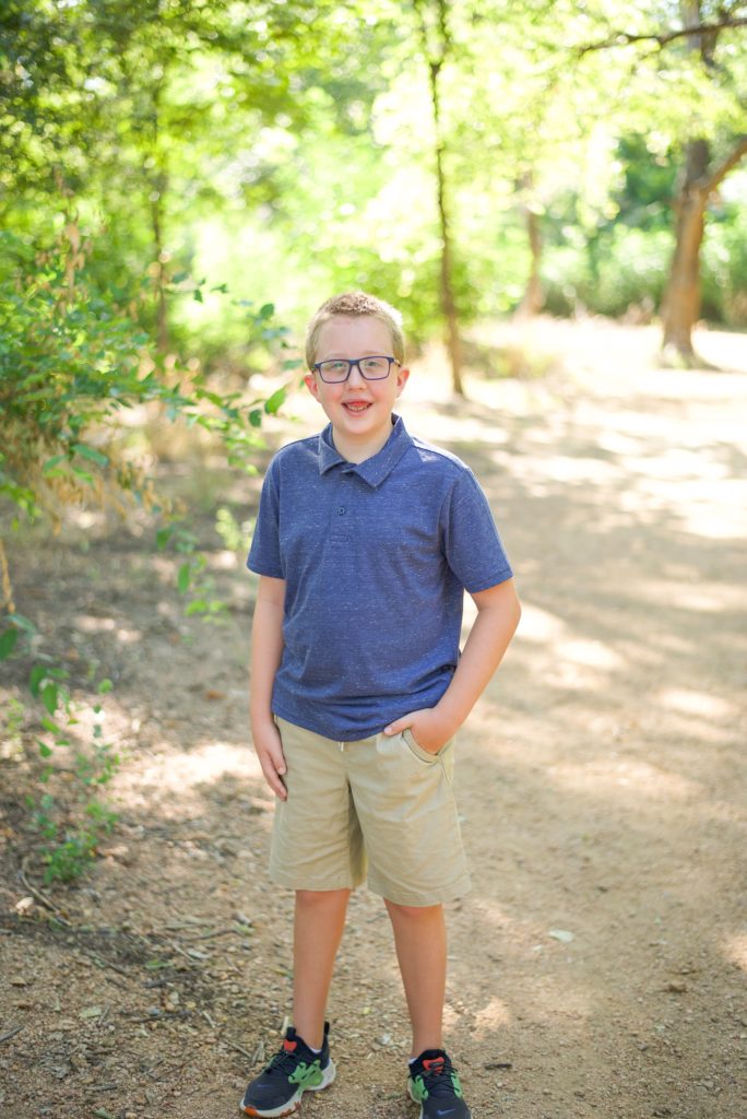 boy in blue polo with khakis poses on trail in Beard Park