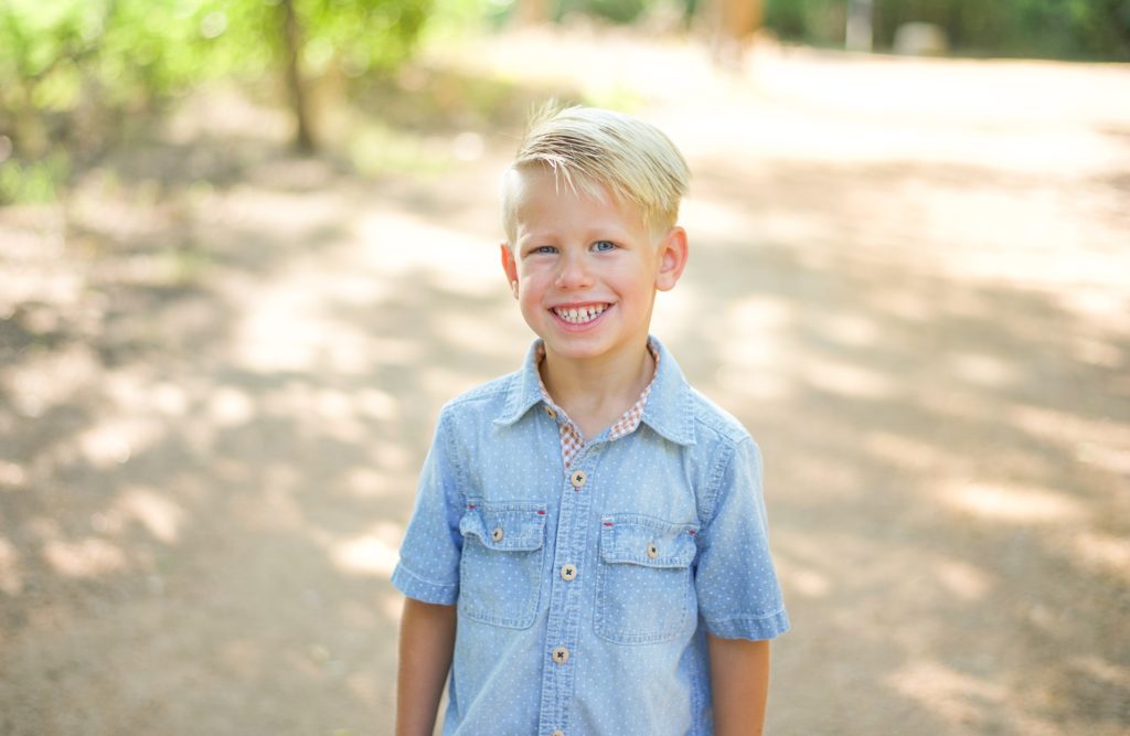 boy in blue shirt smiles on trail in Beard Park