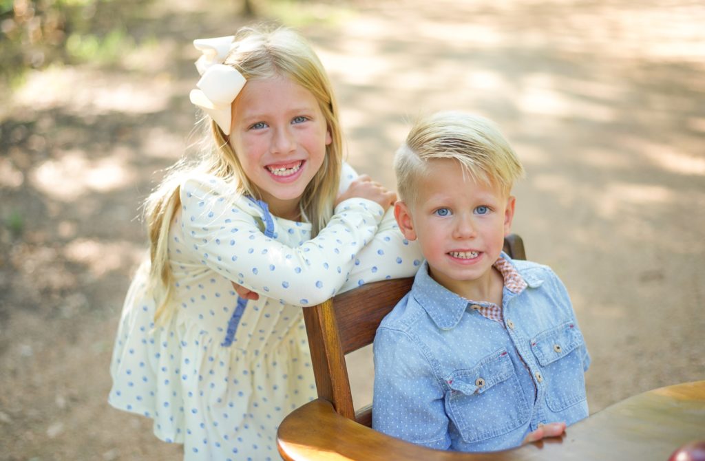 siblings pose together in wooden desk for Back to School Mini Sessions