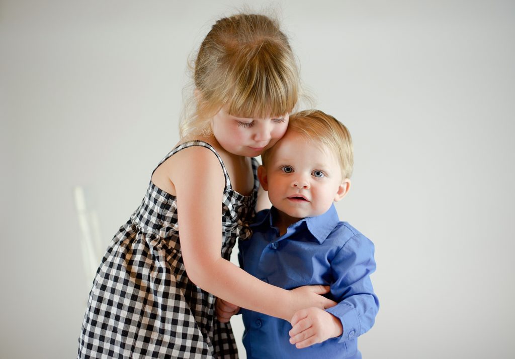 toddler hugs sister during Texas studio portraits