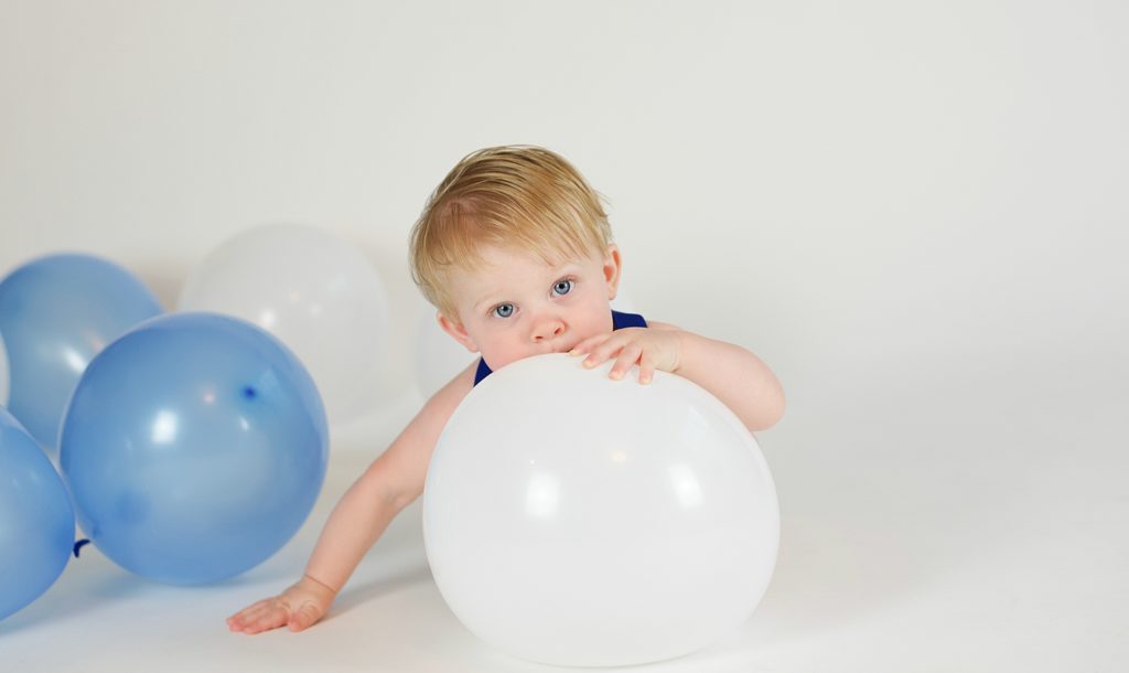 toddler plays with white balloon during Texas first birthday cake smash