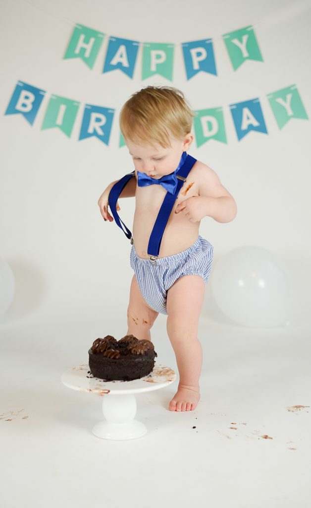 Little Elm first birthday cake smash with toddler in suspenders