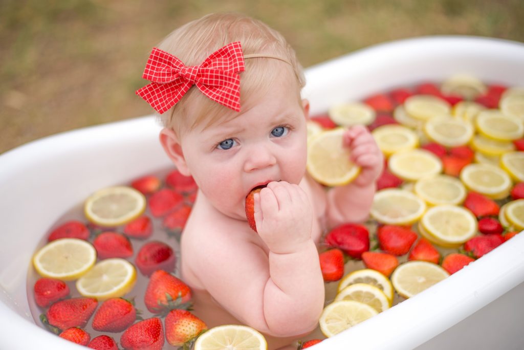 toddler eats strawberry during fruit bath for Texas milestone photos