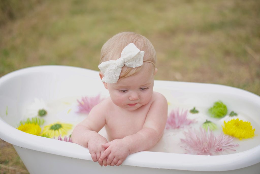 toddler plays in bath tub during Milk Bath Milestone Portraits