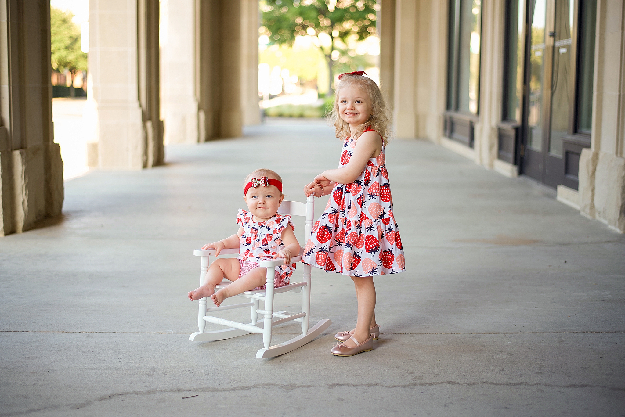 sisters in matching strawberry dresses pose in Frisco TX