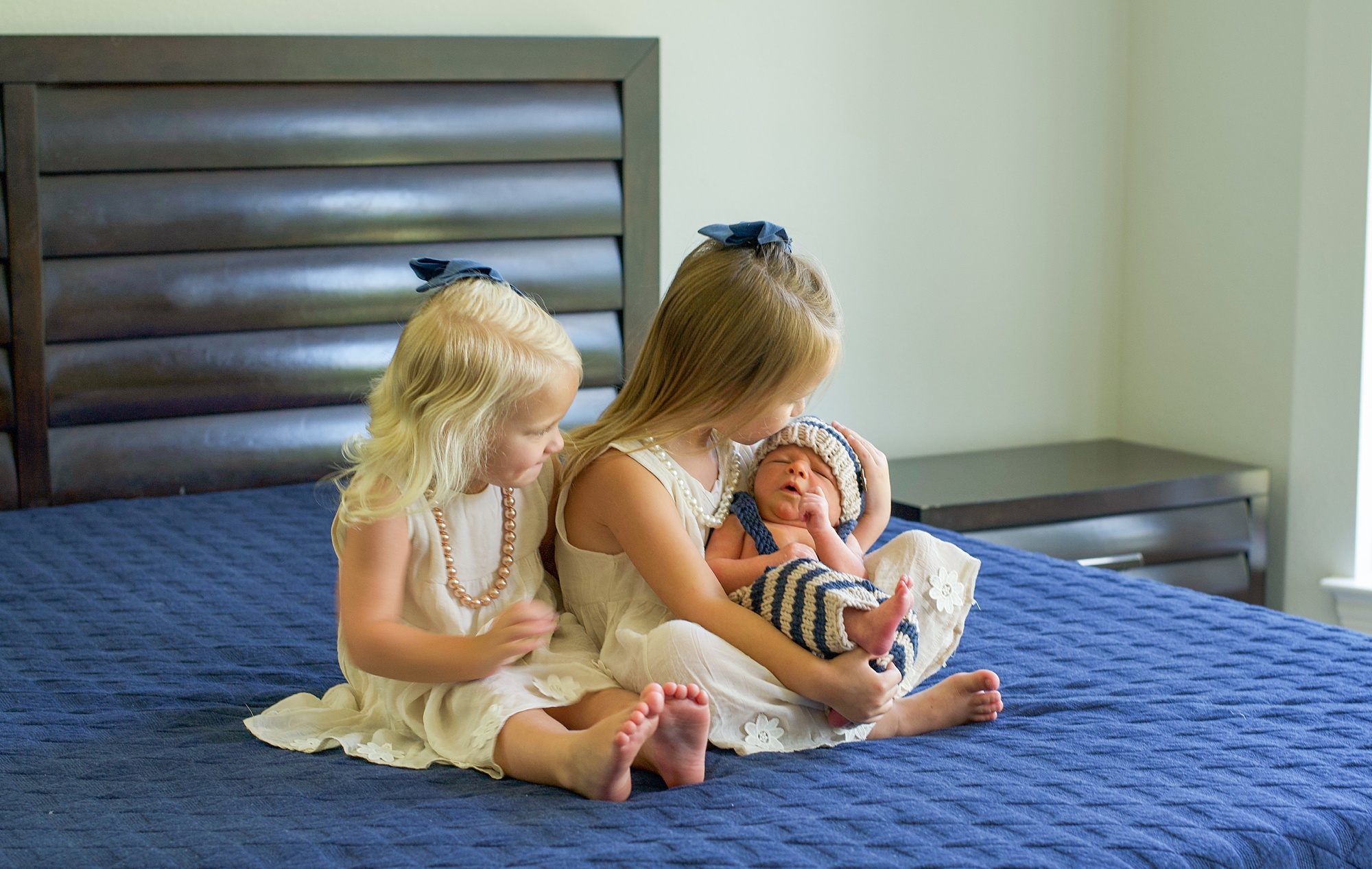 big sisters hold little brother during Little Elm Lifestyle Newborn Session