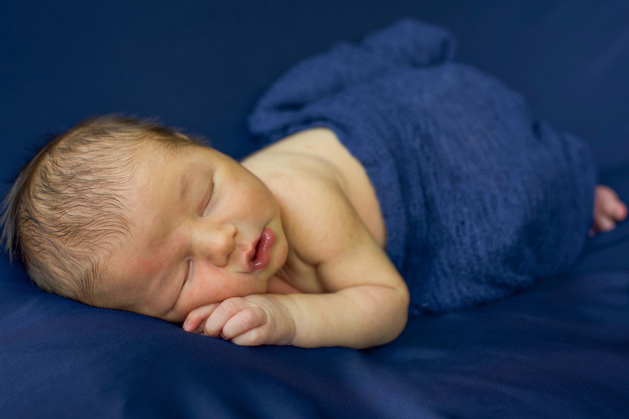 baby boy lays on blue sheets during Little Elm Lifestyle Newborn Session