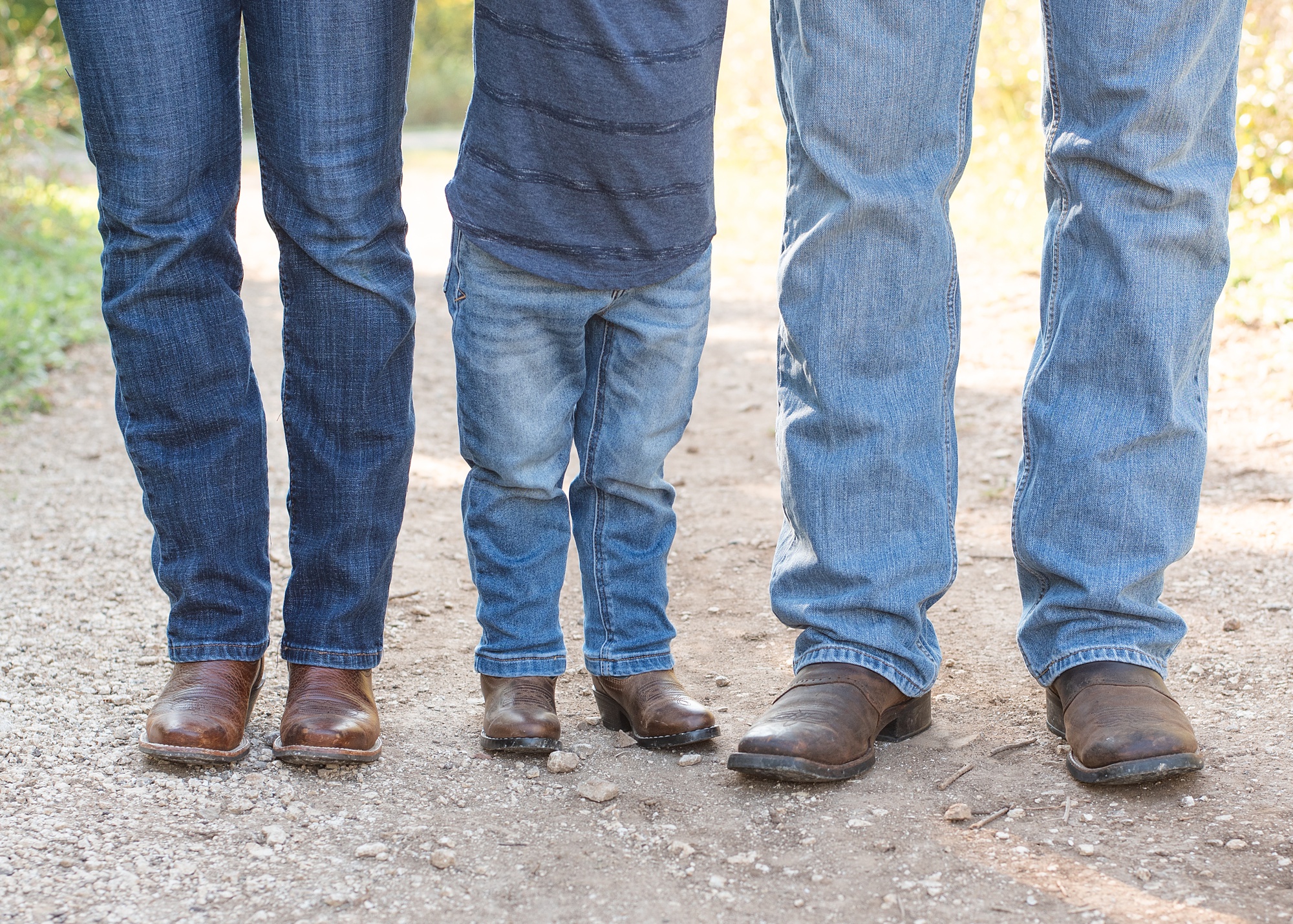 son stands between parents wearing cowboy boots
