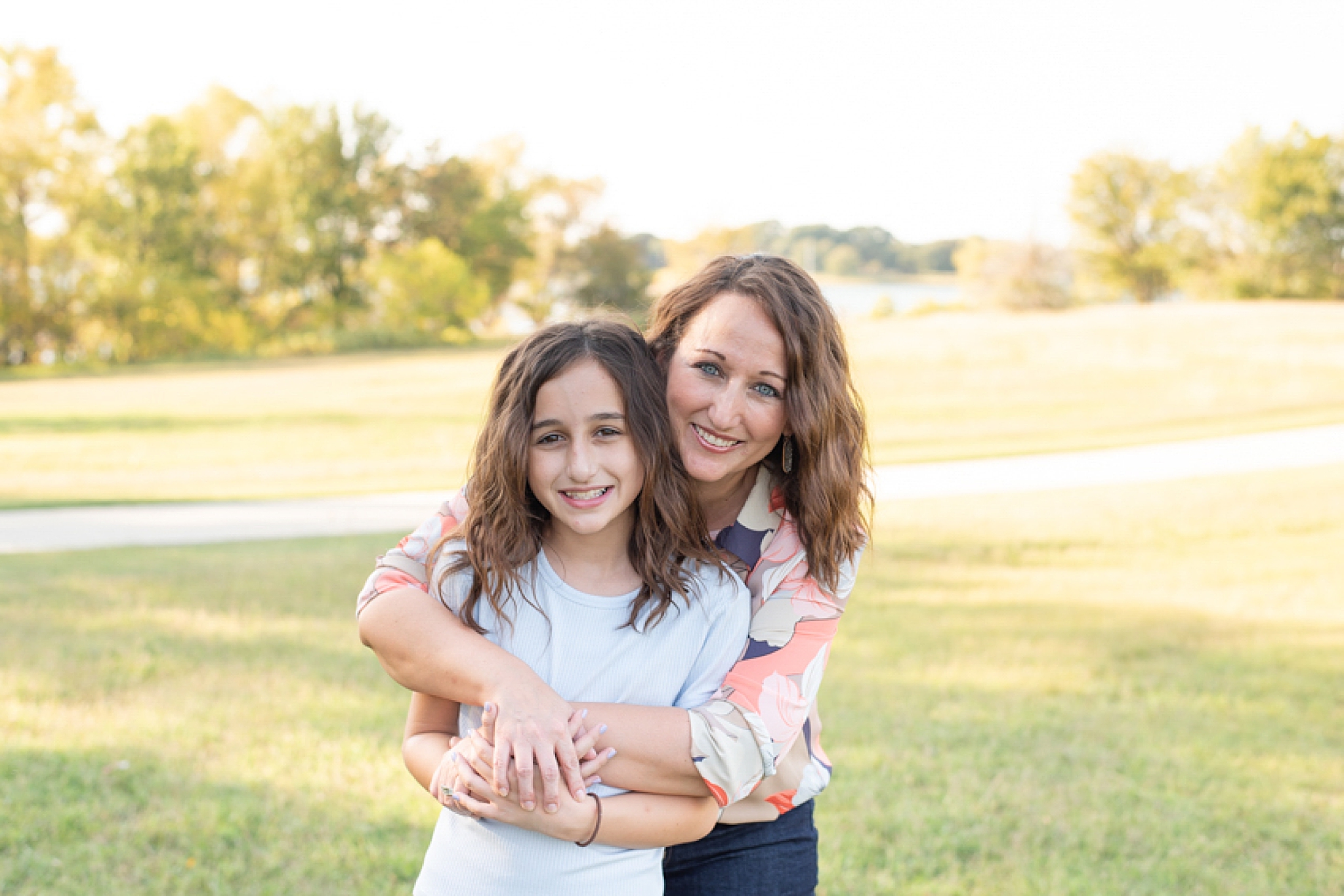 mom hugs daughter during family photos in the park