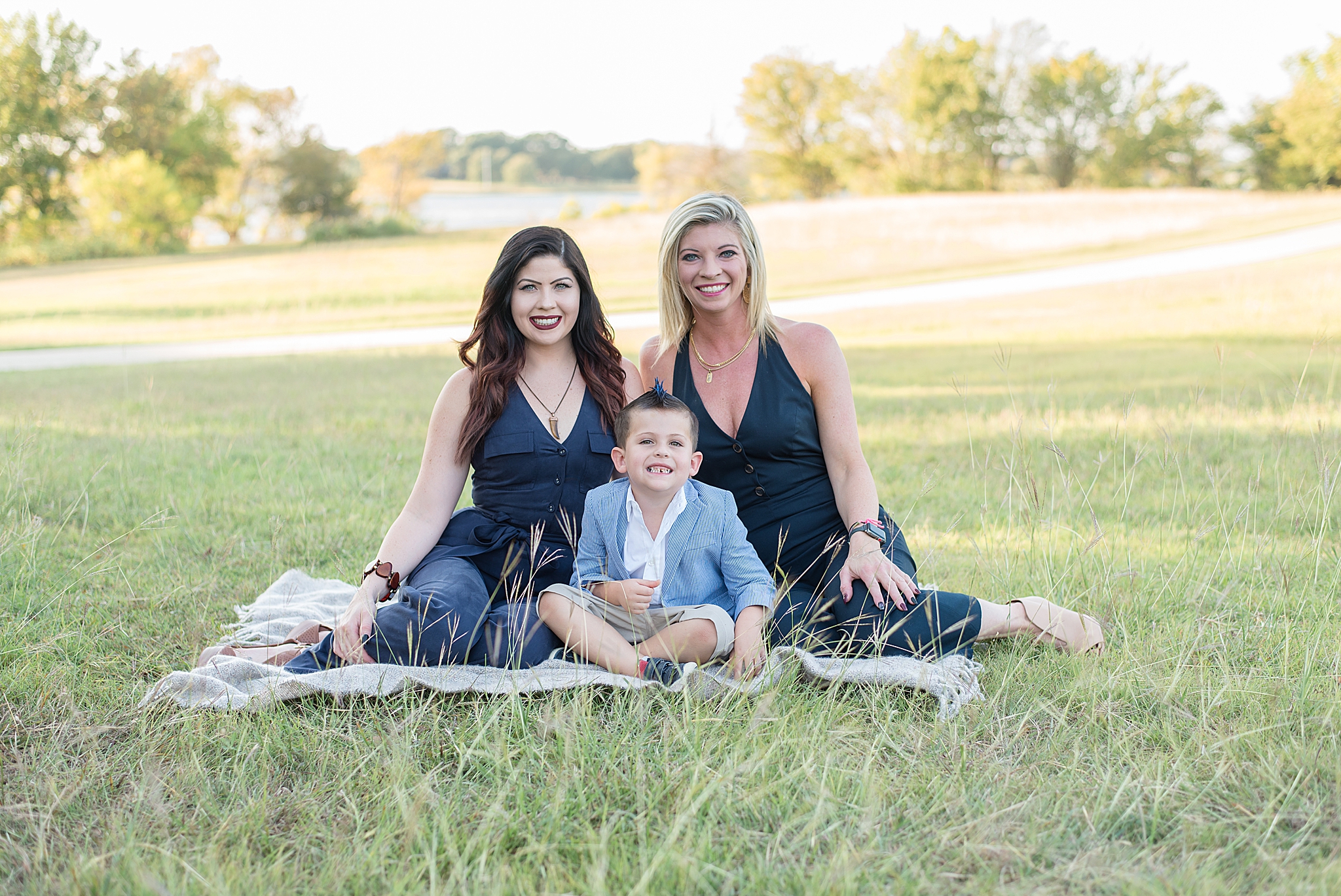 boy sits with his mom and aunt in jumpsuits during Little Elm Park family photos