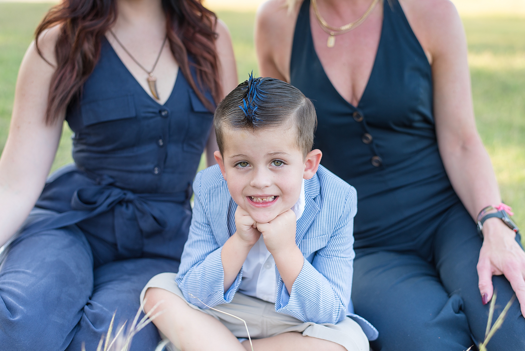 young boy in blue dress jacket leans on fists during family photos