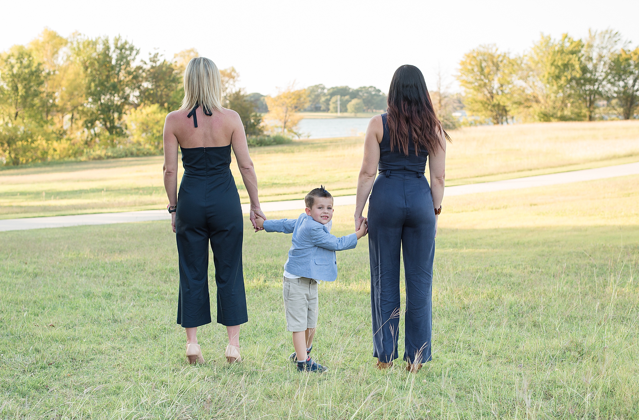 sisters hold boy's hands during photos in Little Elm Park