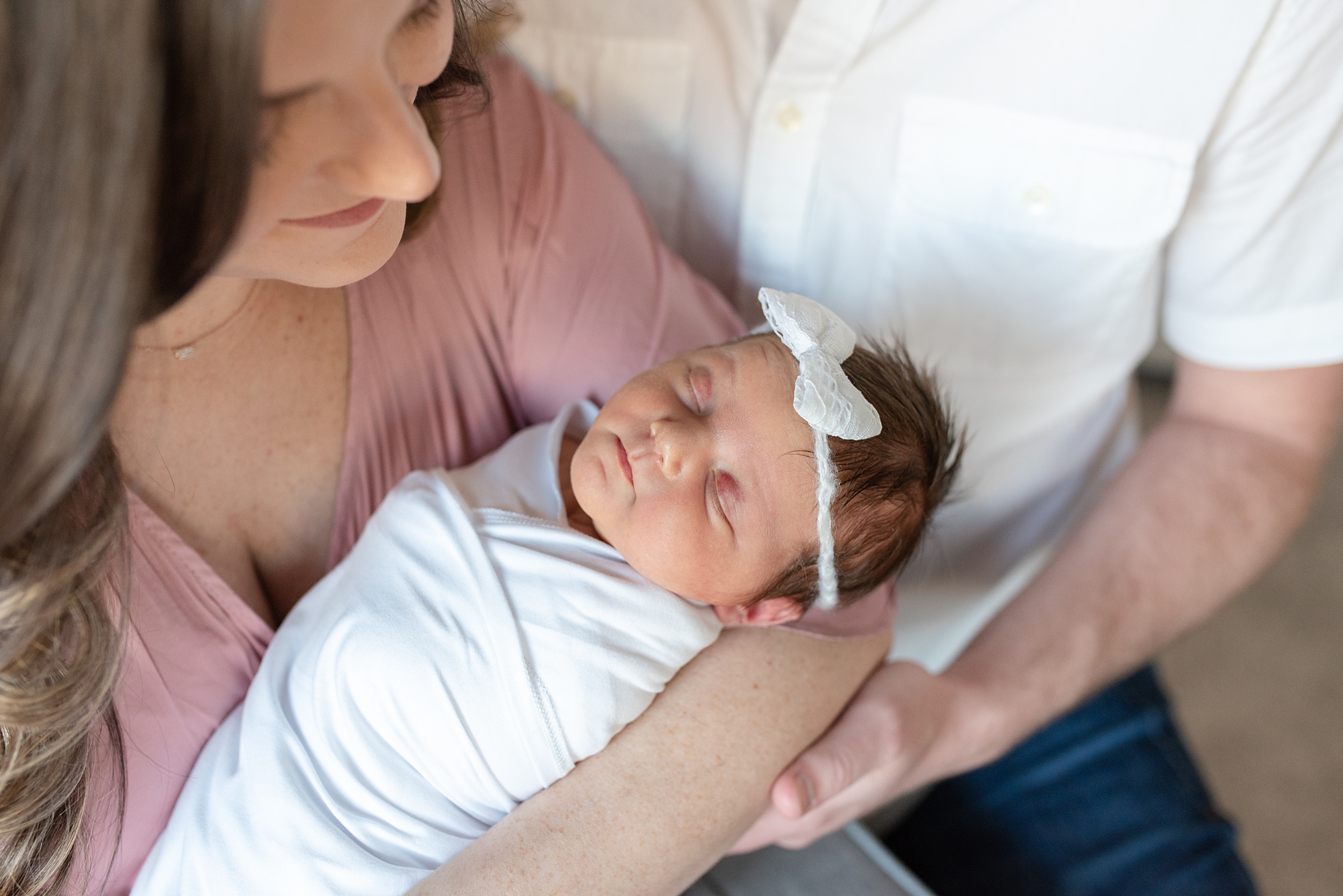 mom looks down at baby in arms during Aubrey TX lifestyle newborn session 