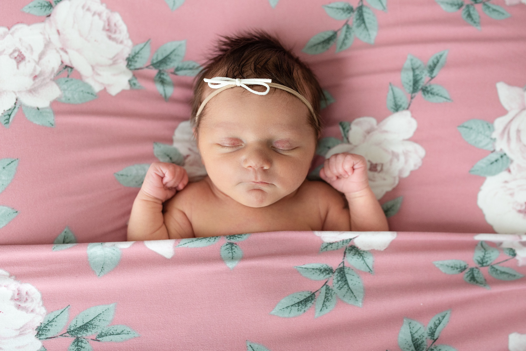 baby sleeps on pink sheets during newborn photos at home