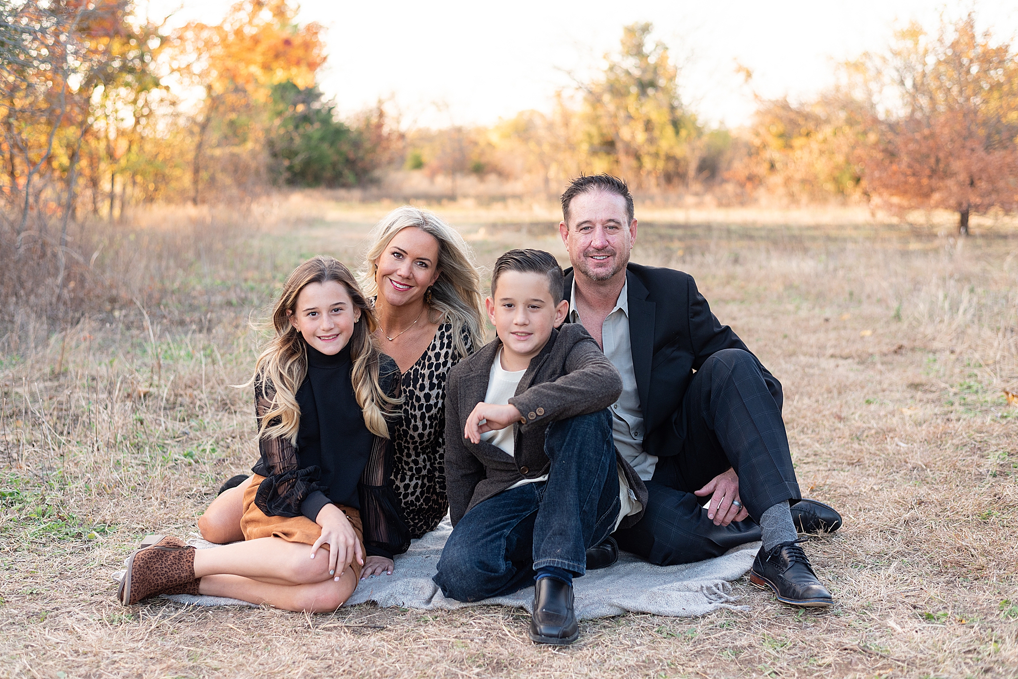 family of four sits on blanket during fall Frisco Field Mini Sessions