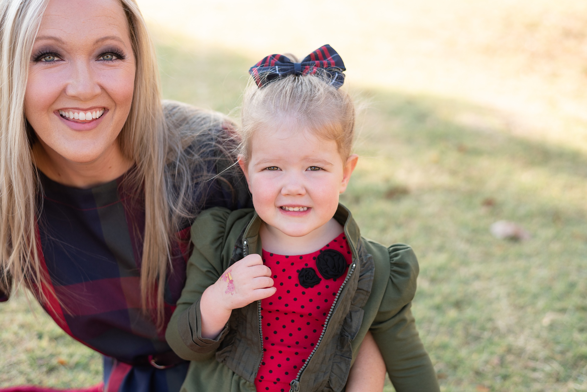 little girl in red dress sits with mom during holiday family photos 