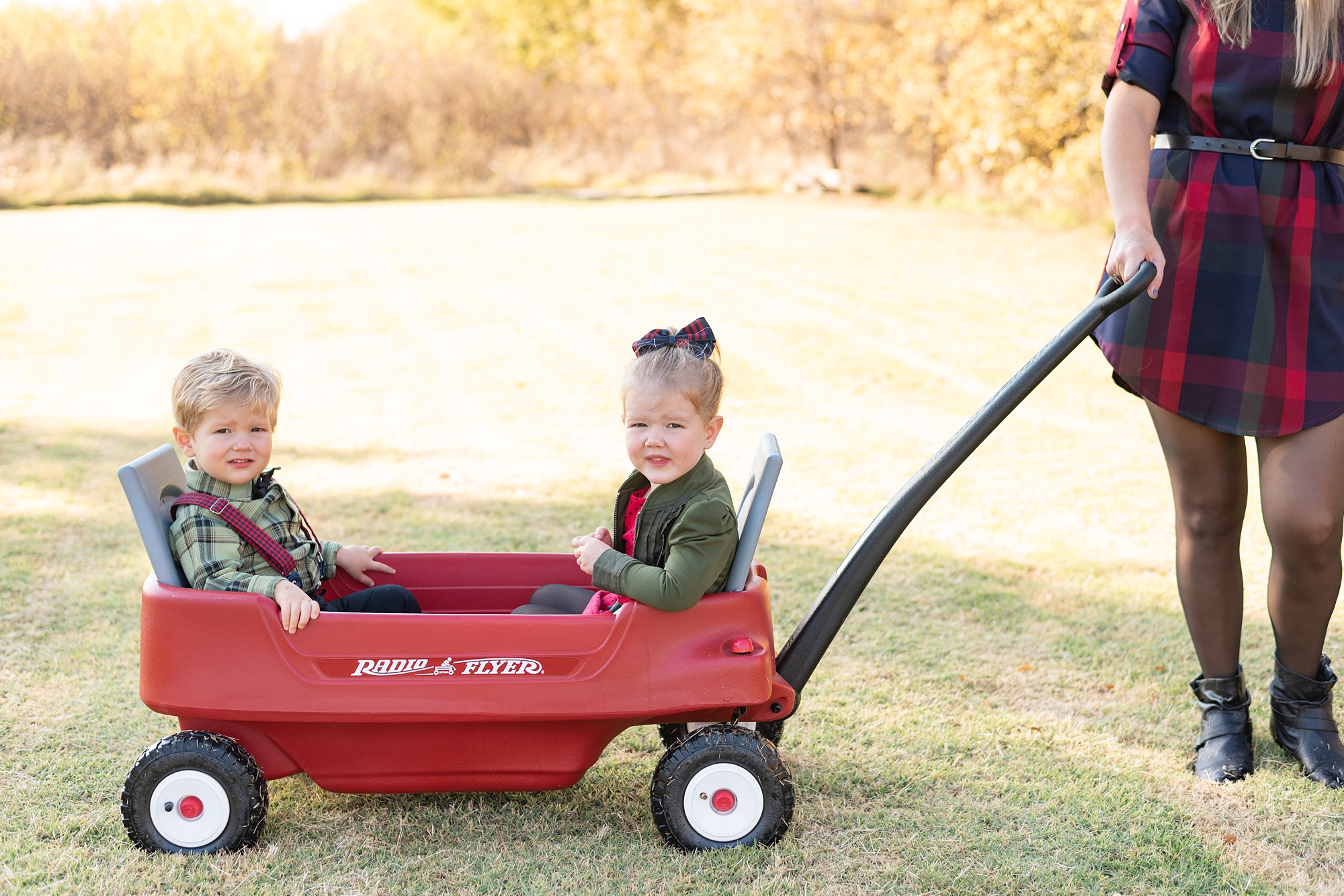 siblings sit in red wagon during Texas family photos 