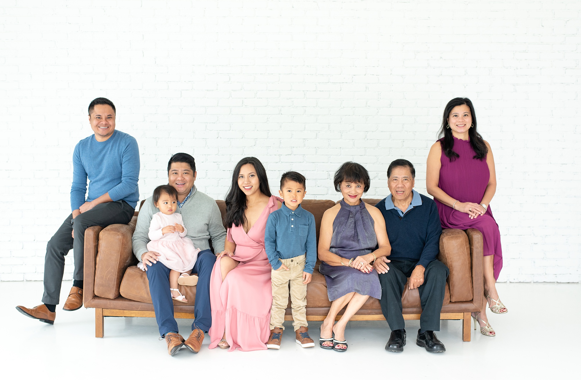 extended family sits on couch in white room of Lumen Room