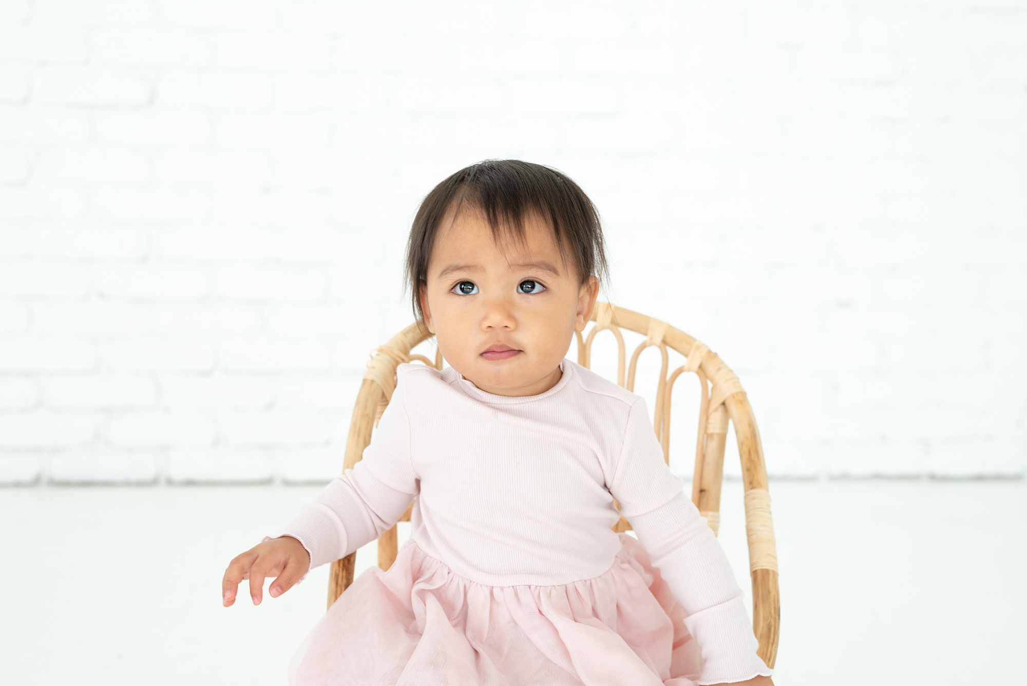 toddler girl in pink dress sits on wooden chair during TX family photos 