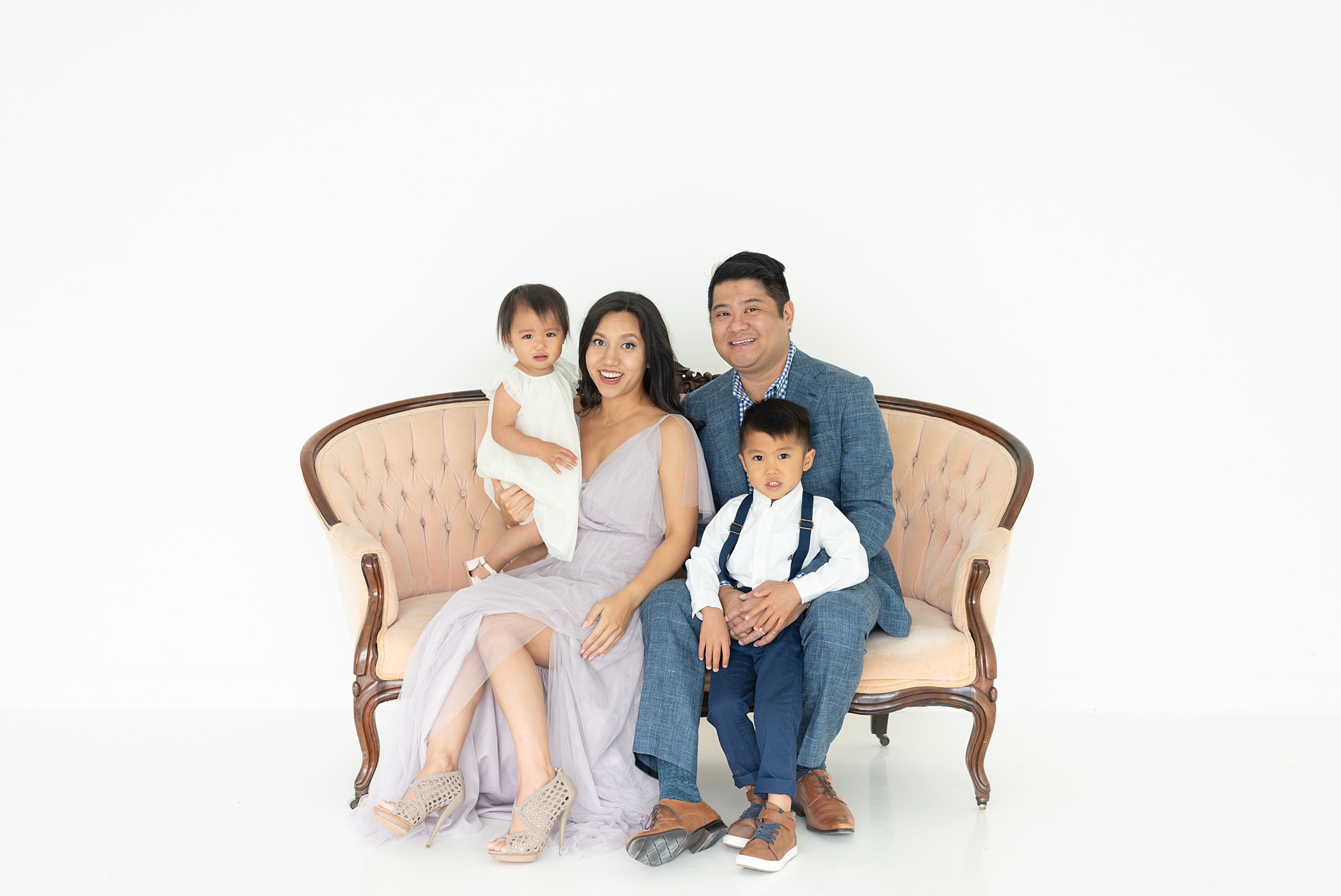 family of four sit on couch during Lumen Room family portraits