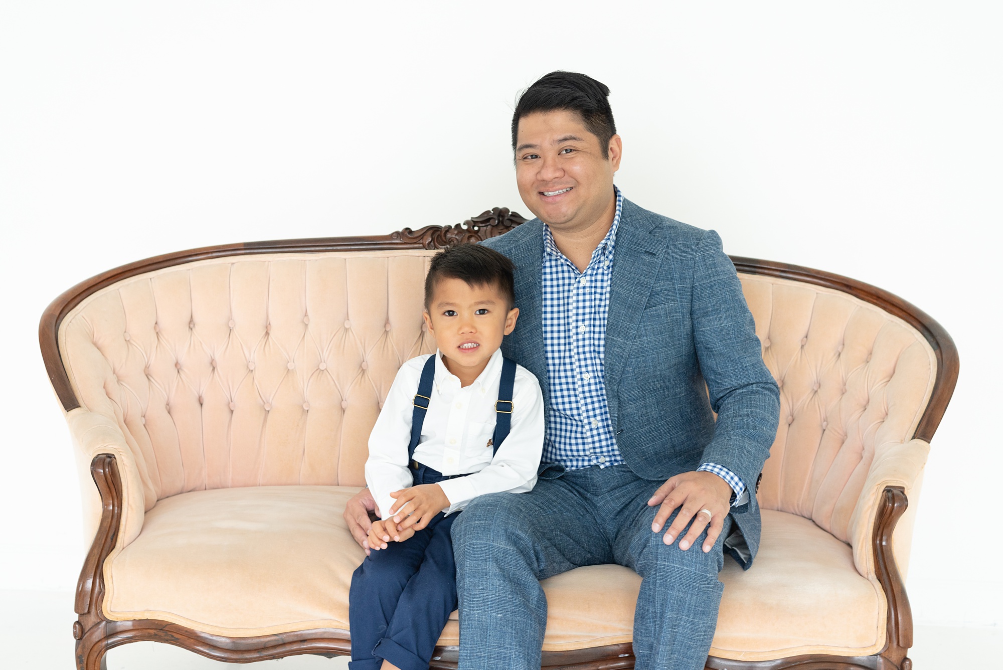 dad sits with son on couch during Texas family photos 