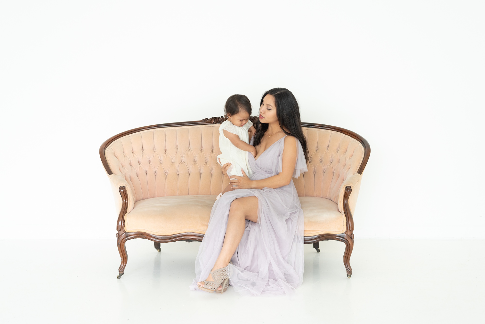 mom and daughter sit on pale pink couch in the Lumen Room