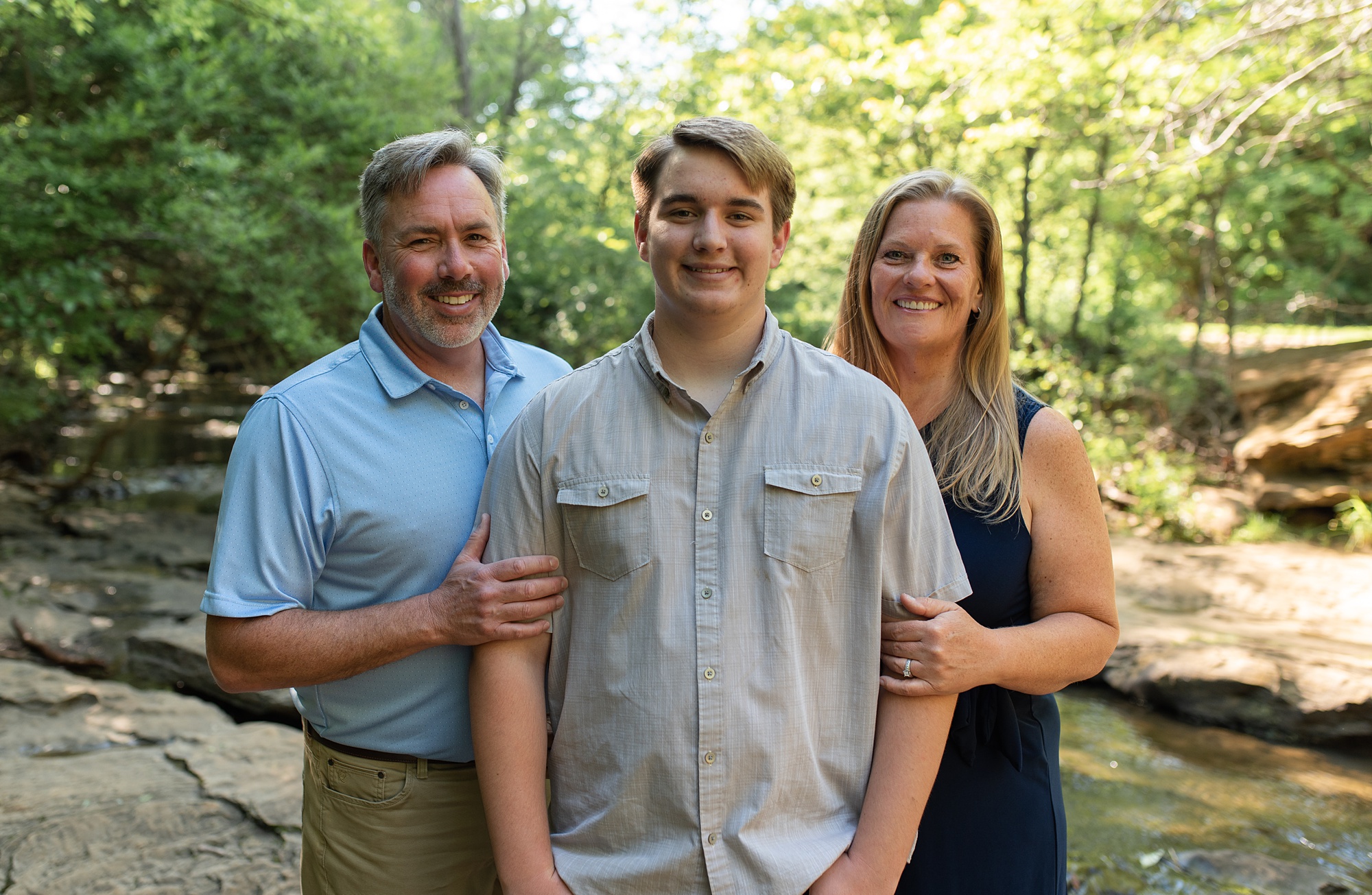 parents stand with teenage son during Stone Creek Park family portraits 