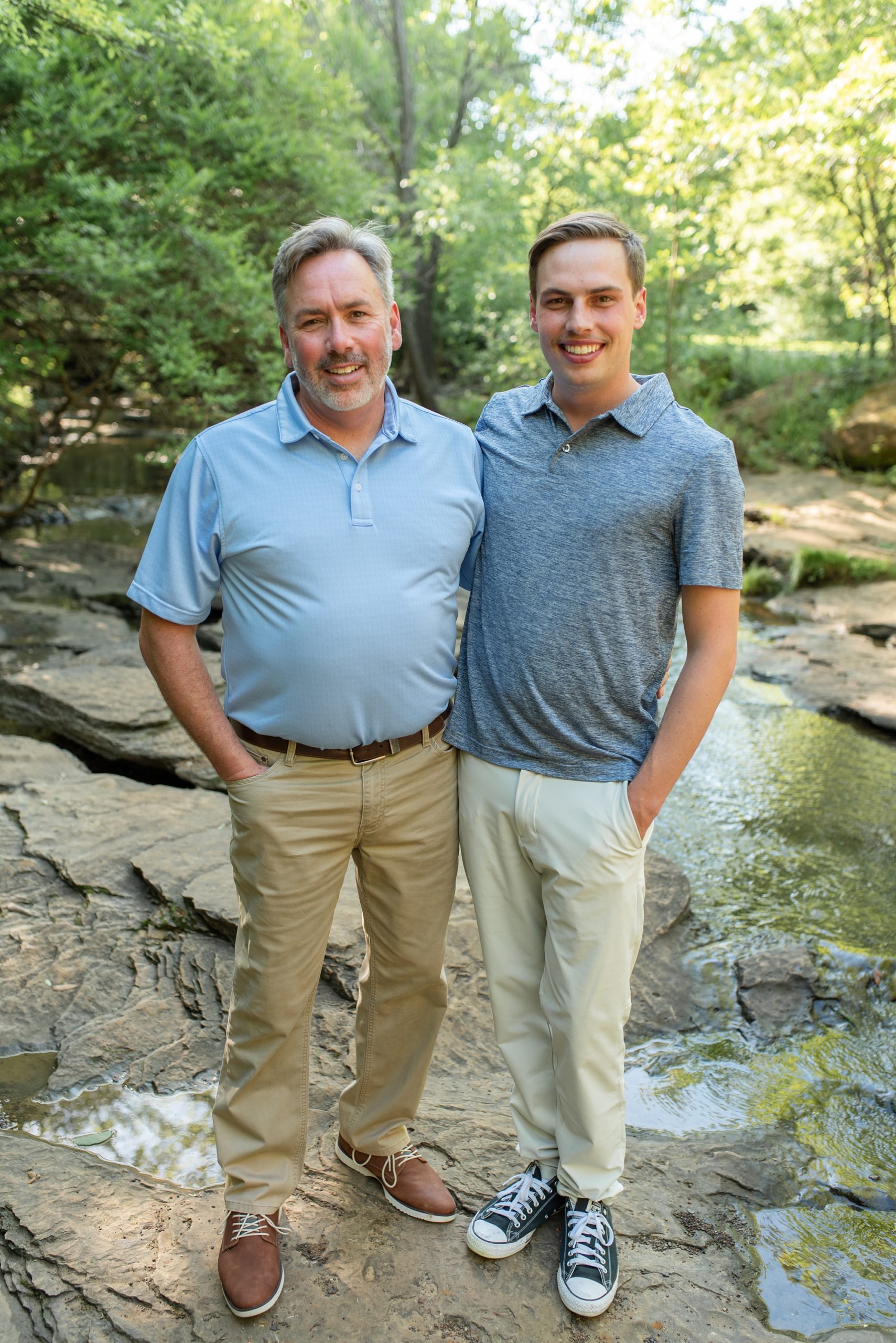 dad poses with son on rock bed