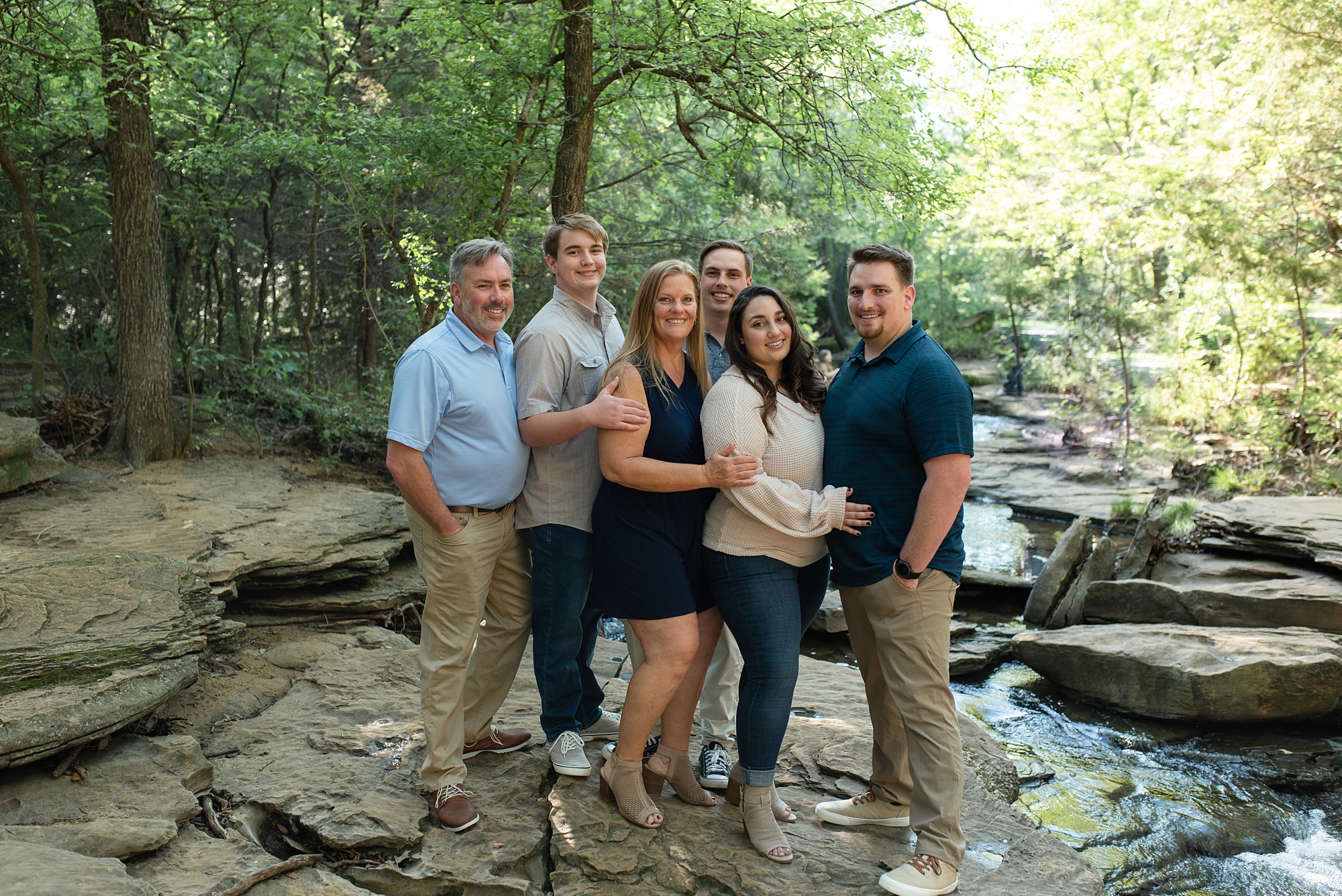 family poses together on rock bed in Stone Creek Park