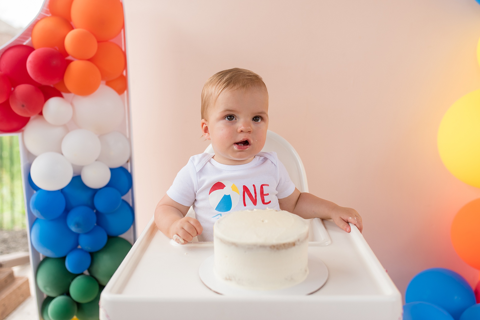 baby eats cake during first birthday pool party