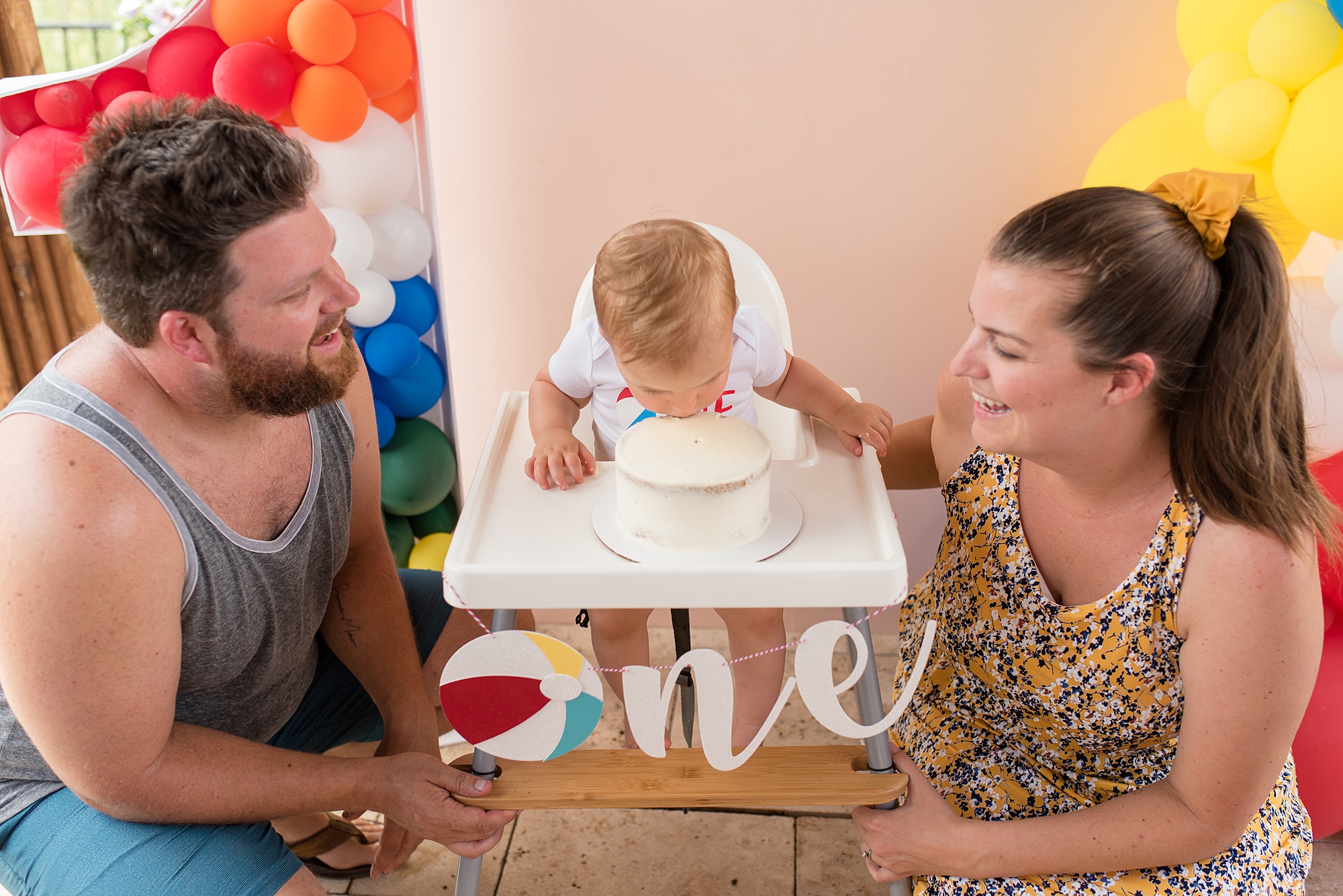 baby smashes cake during first birthday pool party