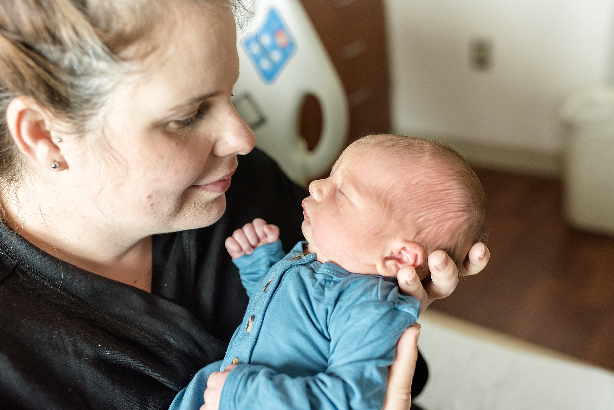 mom looks at baby boy during newborn photos in hospital 