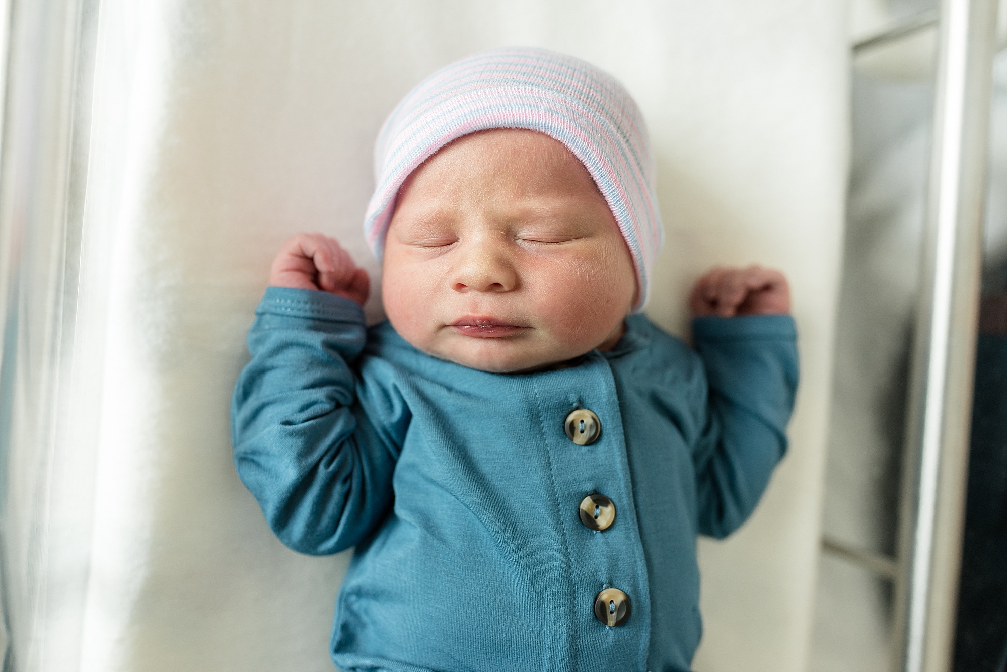 baby lays with arms bent upwards during hospital newborn photos
