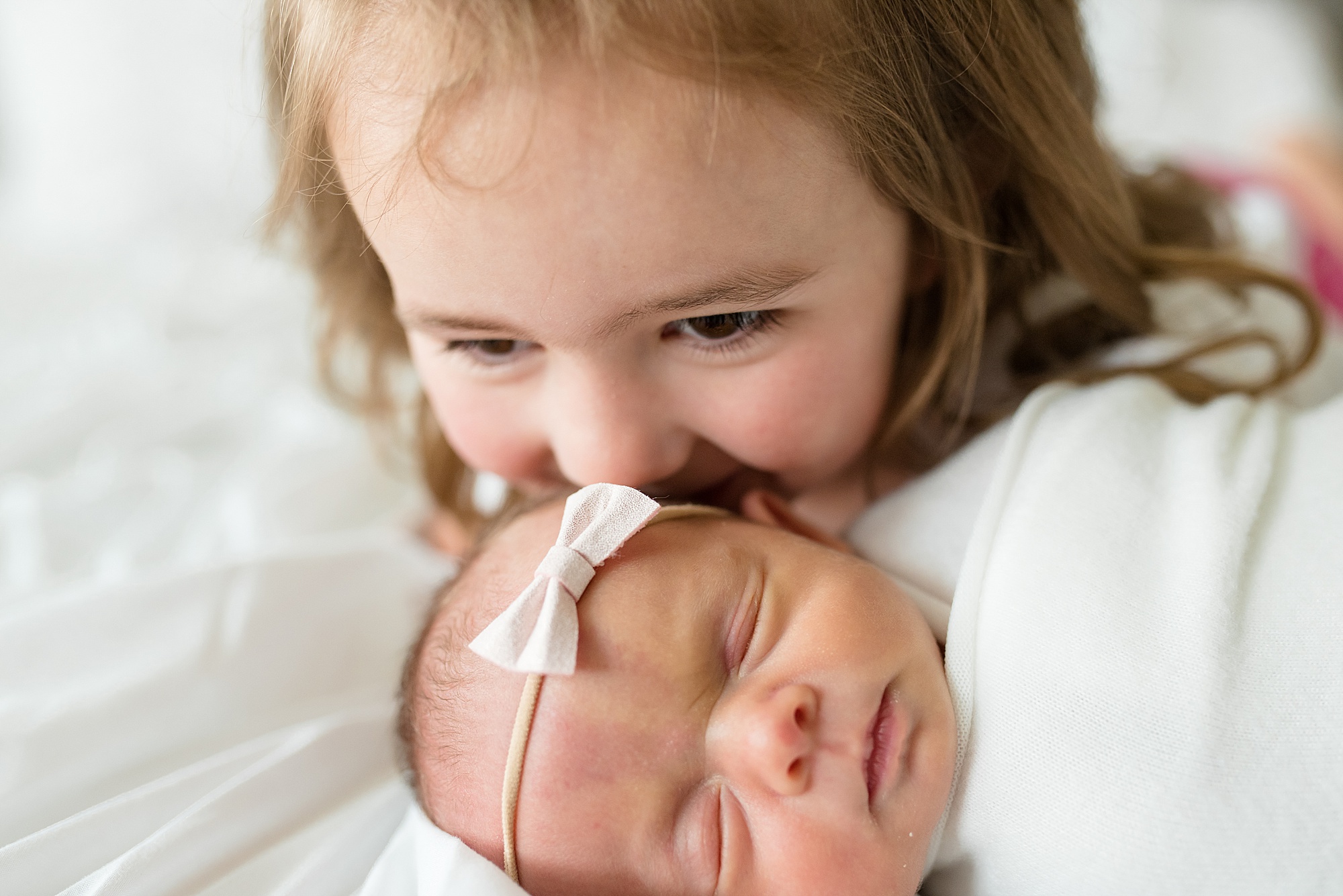 big sister kisses little sister during newborn photos in Prosper TX
