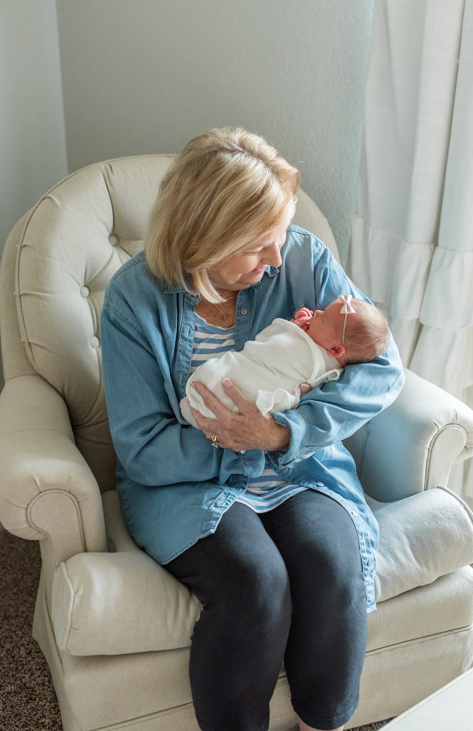 grandmother holds baby girl in arms during newborn photos in nursery 