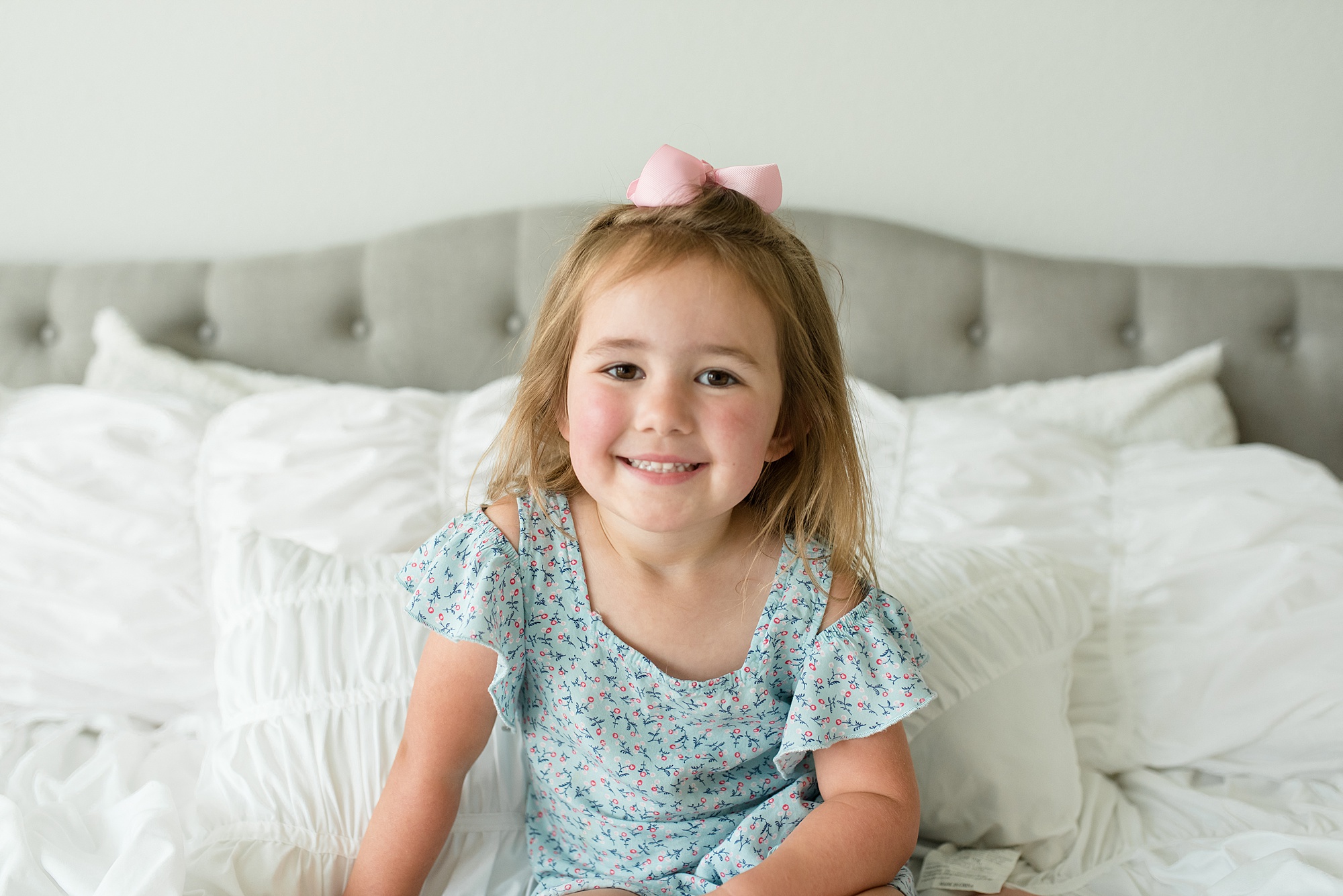 toddler sits on bed during family photos at home
