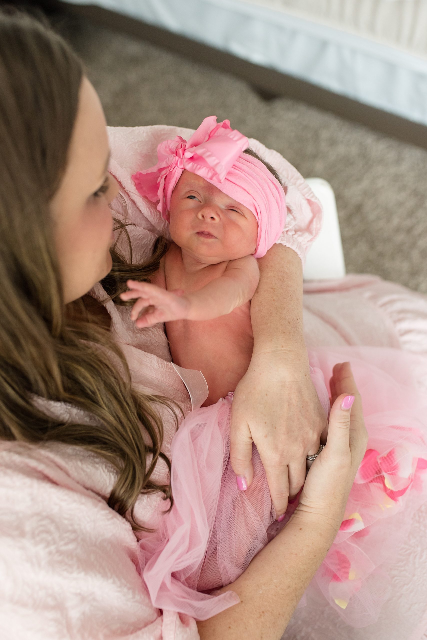 mom holds baby girl in pink tutu during in-home lifestyle newborn session