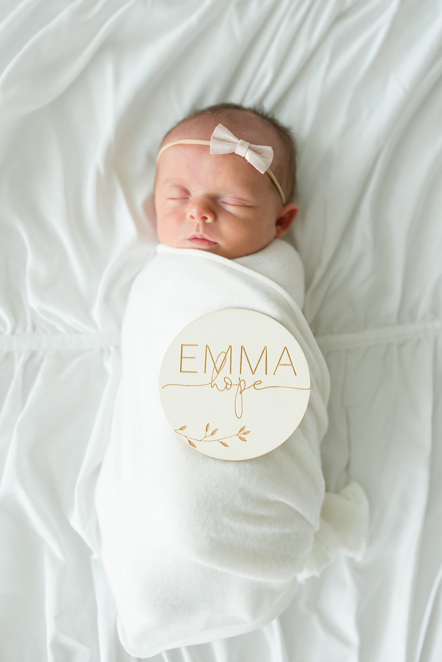 baby lays with "Emma" sign on her 