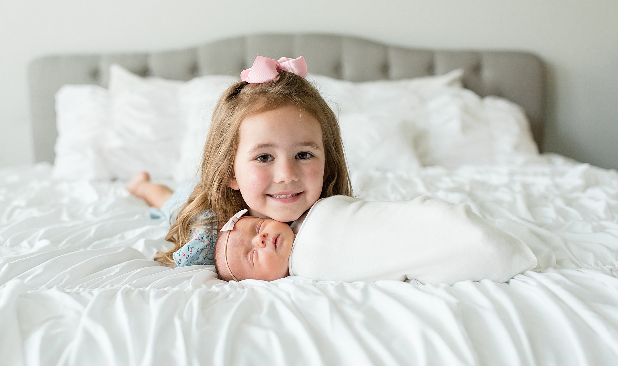 big sister lays with newborn sister during in-home lifestyle newborn session