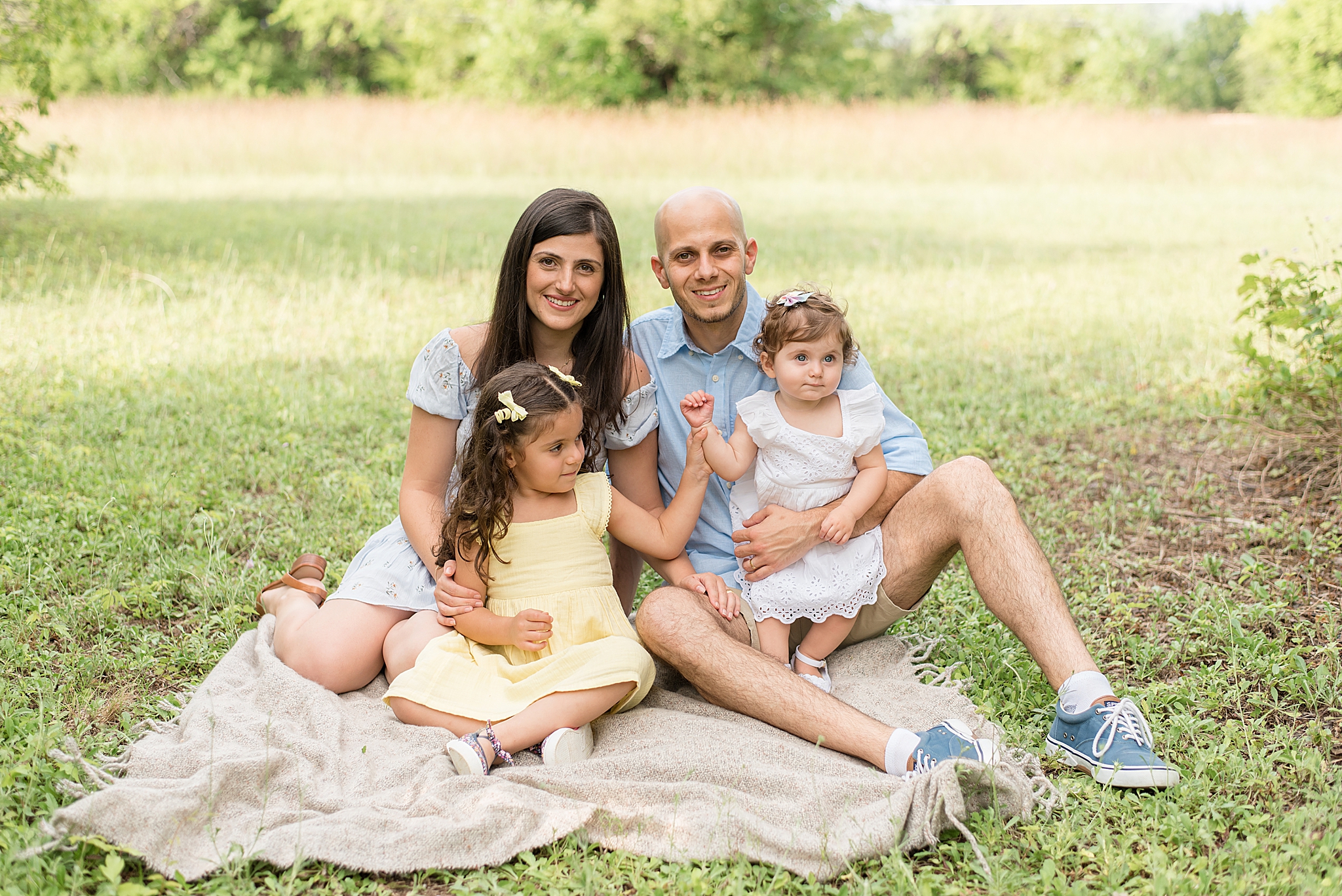 family of four sits on blanket during Milestone Portraits in Frisco