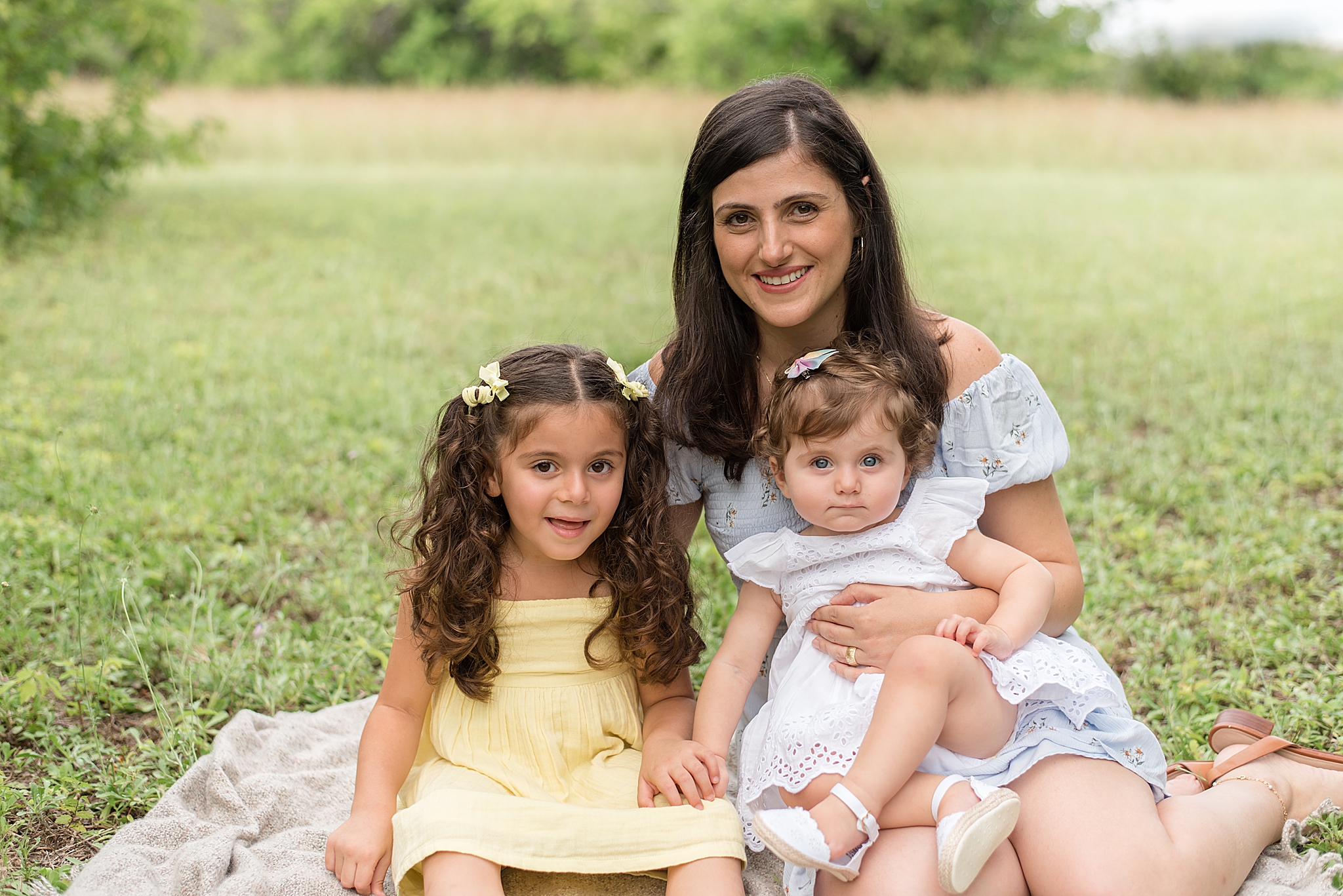mom sits with daughters during family photos in Texas