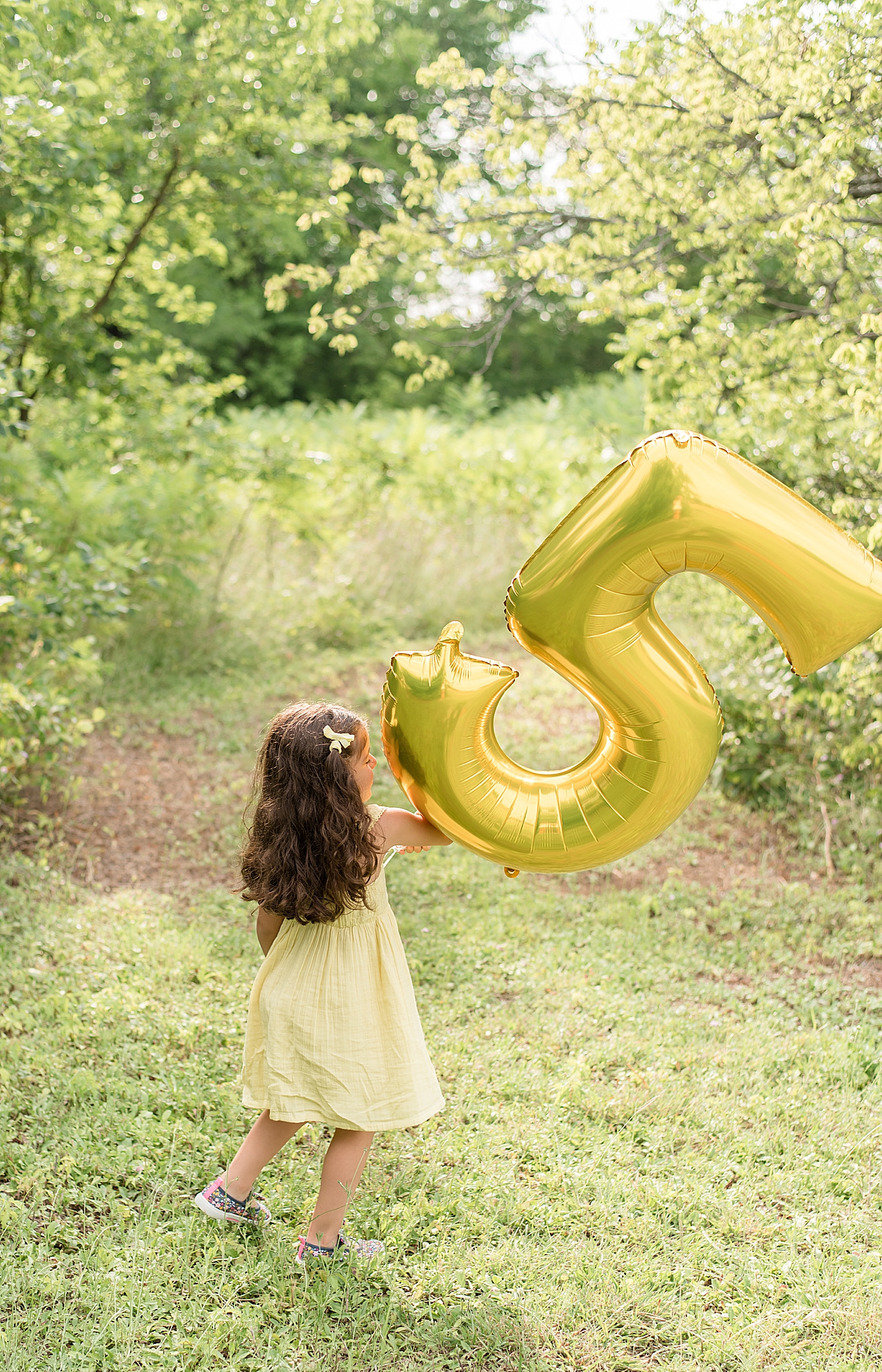 five year old walks with golden 5 balloon