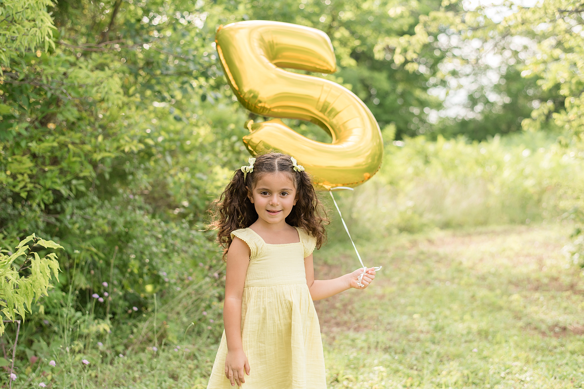 five year old holds 5 balloon