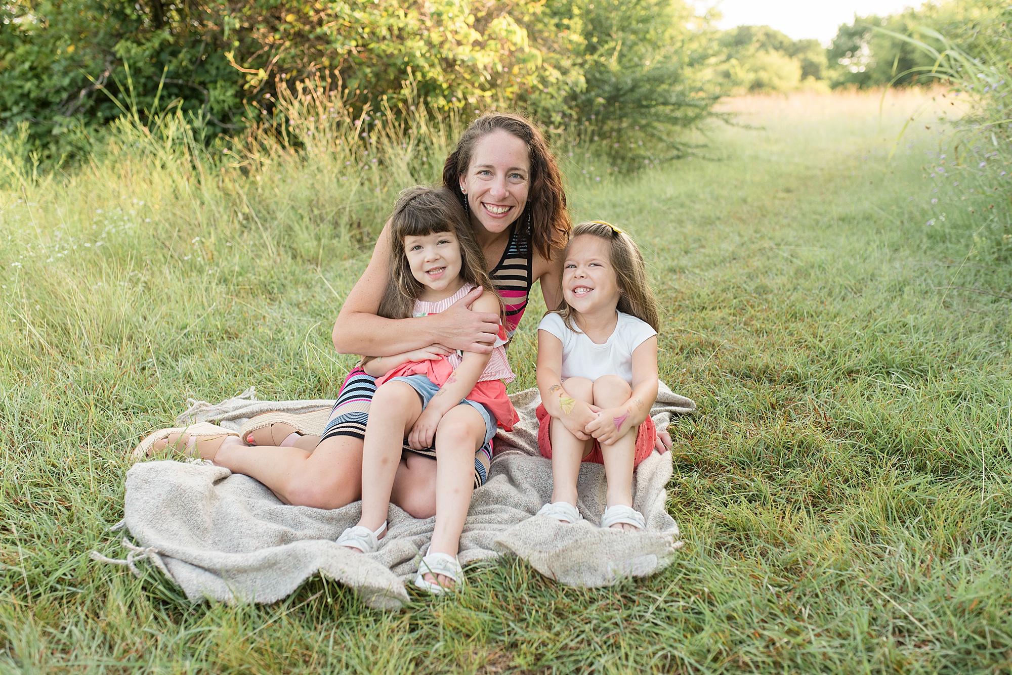 moma and her two little girls sitting in the green grass of Texas