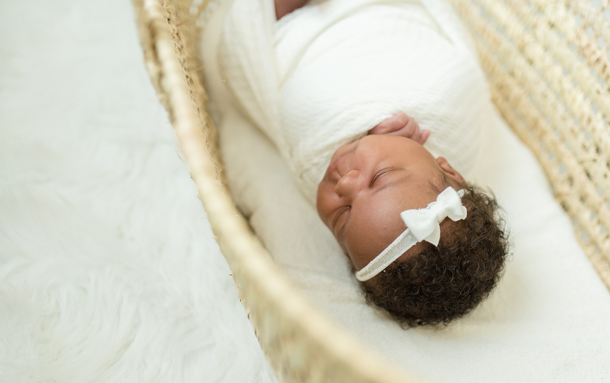 newborn baby girl sleeps in woven bassinet in Denton TX by Lindsey Dutton Photography
