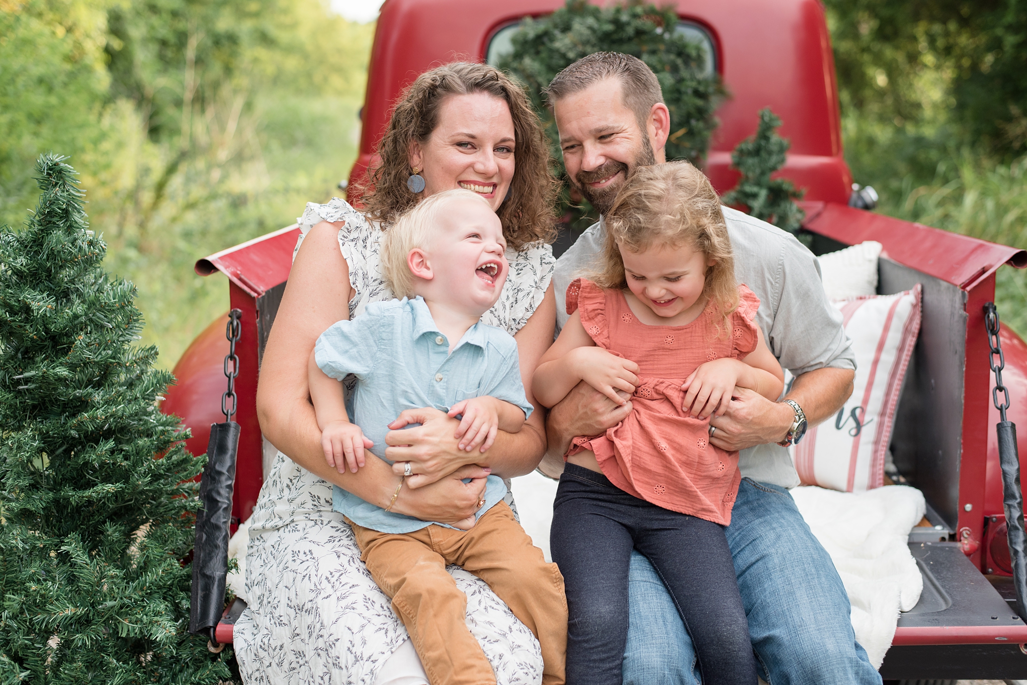 family sits in the back of a red pick up truck during family session