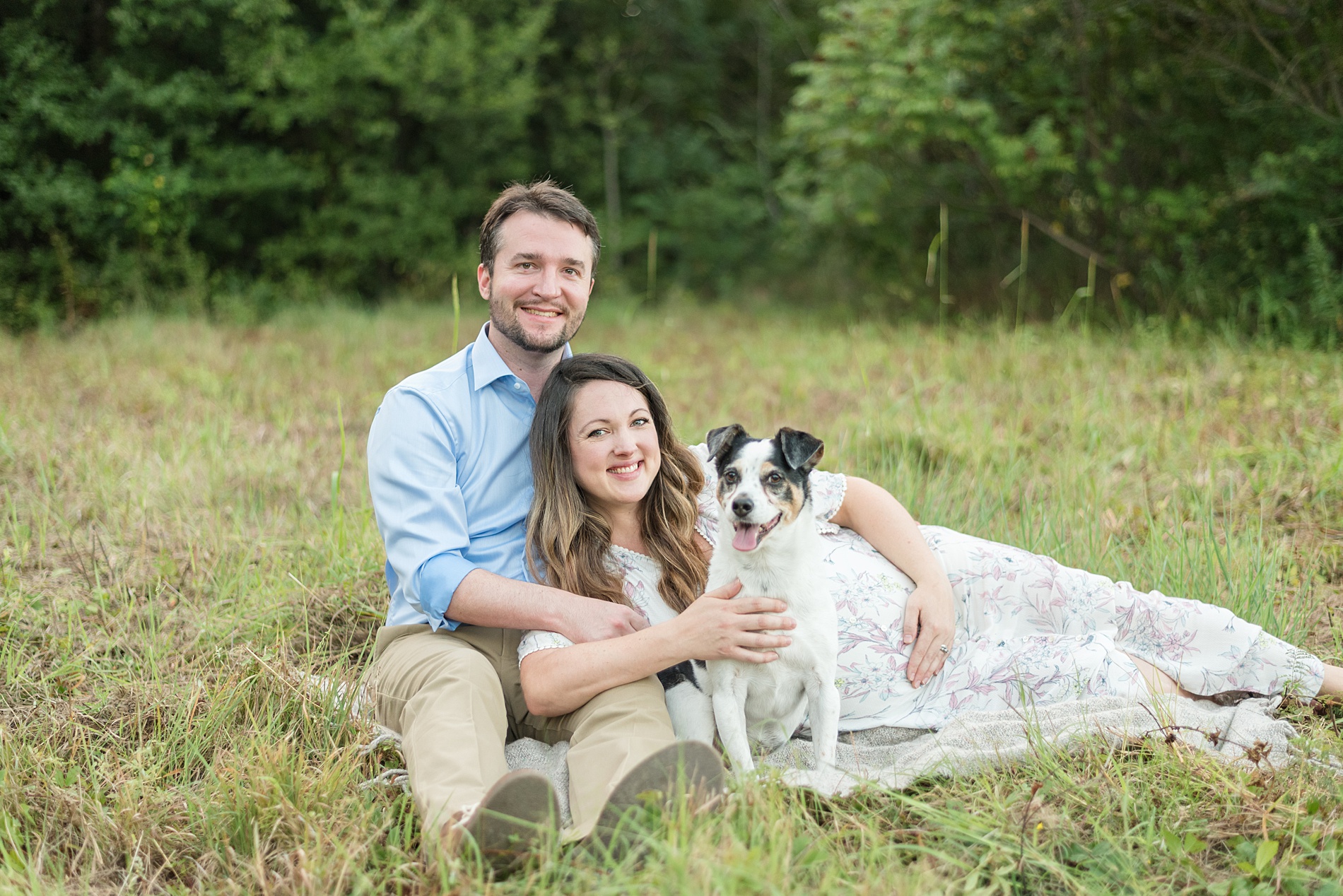 parents to be and their dog sit in grass during Arbor Hills Maternity Session