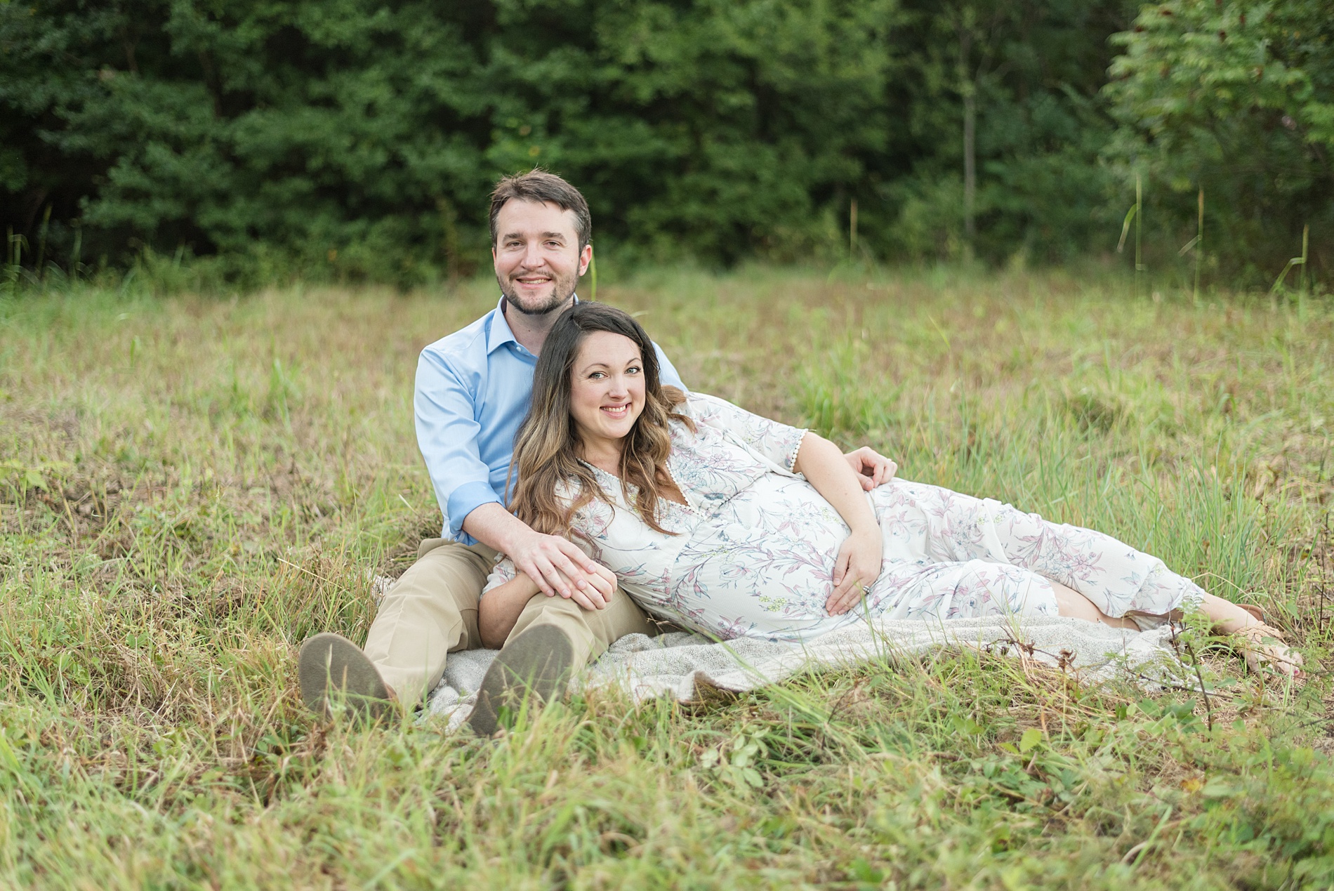 couple lays in grass during maternity session at arbor hills in Plano TX 